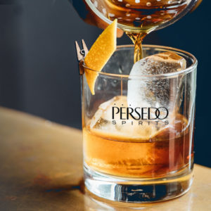 A glass of bourbon with the Persedo logo